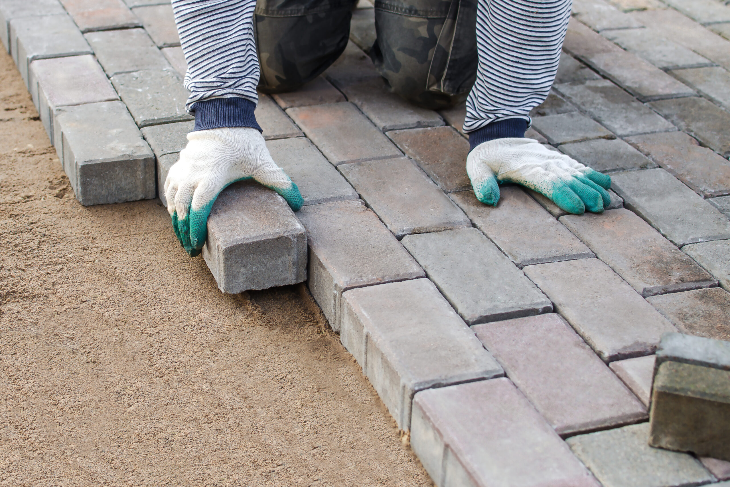 hombre-adoquines-en-la-acera-colocacion-de-losas-de-pavimento-en-el-patio-sobre-una-base-de-cimentacion-de-arena-nivelada